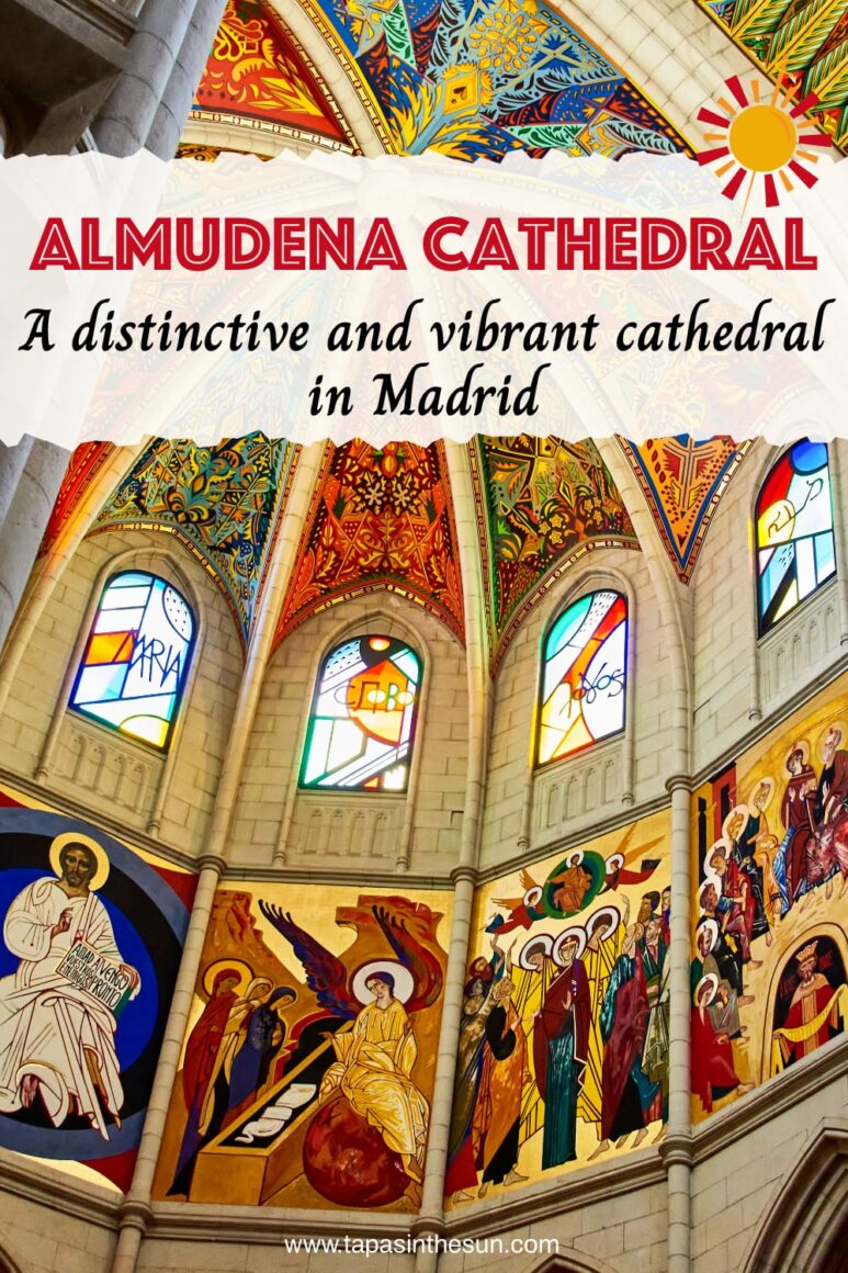 Ornate cathedral interior with colourful painted vaulted ceiling, stained glass windows, and detailed religious frescoes depicting saints and biblical scenes on the stone walls. Light streams through arched windows.