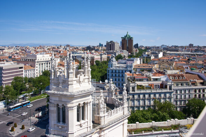 Palacio de Cibeles, Madrid Aerial view of Madrid with historic white stone buildings, city streets, and modern skyscrapers under a clear blue sky on a sunny day.