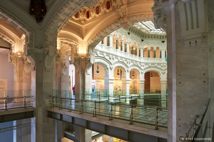 Palacio de Cibeles, Madrid Interior view of a grand, ornate building with arched ceilings, intricate architectural details, white columns, and a glass ceiling, featuring multiple levels and a spacious, open design.