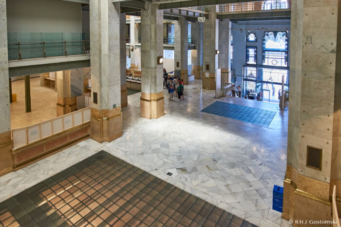 Palacio de Cibeles, Madrid Palacio de Cibeles in Madrid - Spacious, modern entrance foyer with marble floors, tall columns, and large windows. A group stands near the entrance as bright natural light fills the open space.