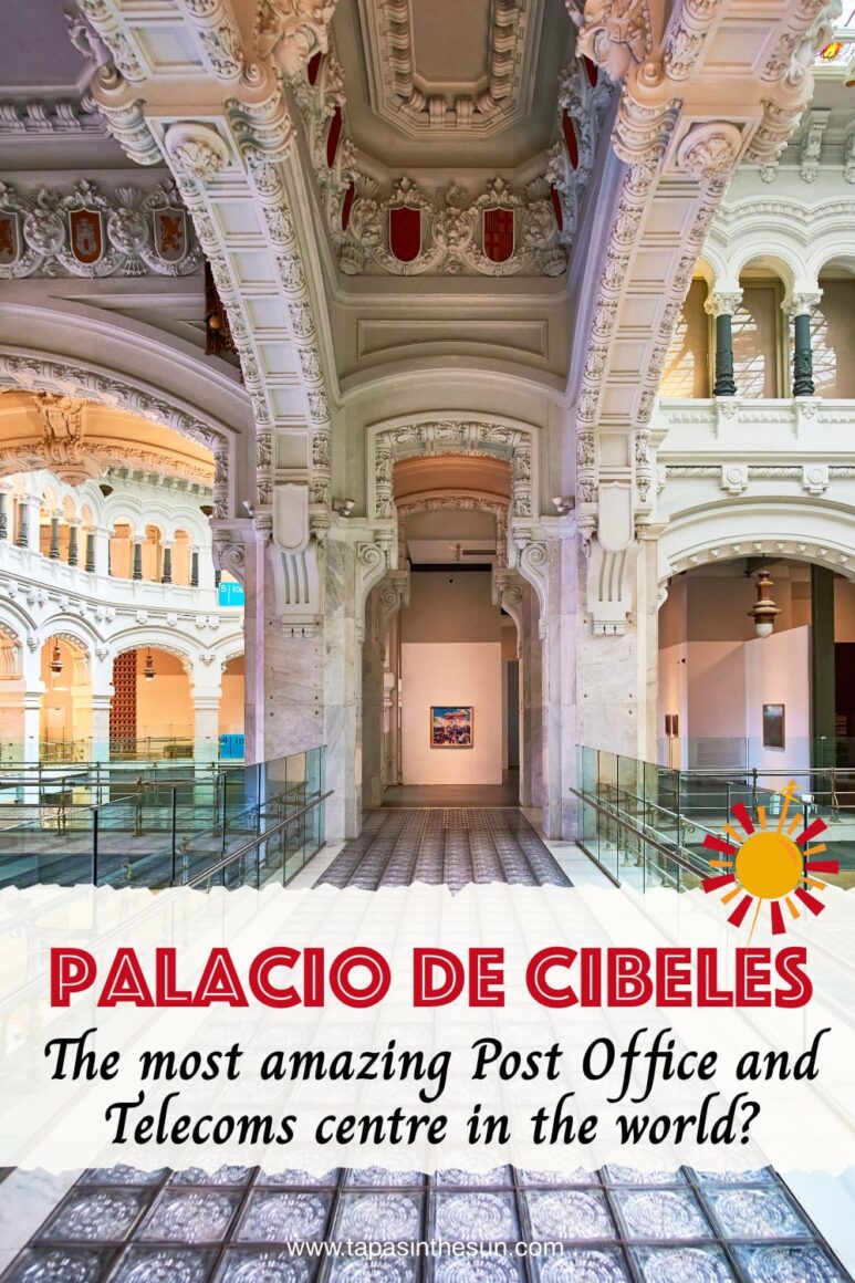Ornate interior of the stunning Palacio de Cibeles, featuring an arched ceiling adorned with intricate carvings and emblems. The glass-tiled walkway is flanked by marble columns, leading towards a brightly lit doorway.