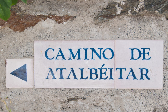 A ceramic sign on a stone wall reads CAMINO DE ATALB&Eacute;ITAR in blue capital letters, with a left-pointing arrow on the left side.
