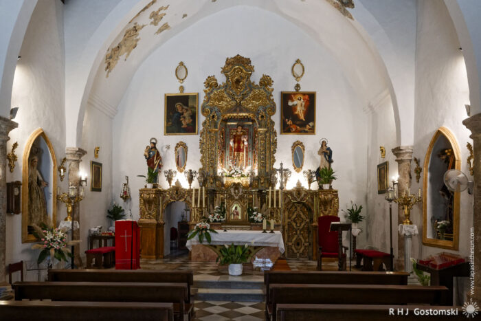 Inside Iglesia San Lorenzo Inside Iglesia San Lorenzo, the ornate church interior features a gold altar, religious statues, large paintings, and floral decorations. Wooden pews face the altar beneath a vaulted white ceiling with patches of original fresco.