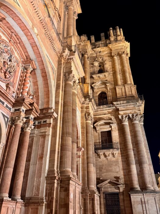 A beautifully illuminated historic cathedral at night, showcasing intricate architectural details, tall columns, and ornate carvings, set against a dark sky. The scene captures the grandeur and elegance of this iconic structure.